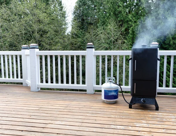 Smoker with fresh smoke coming out of BBQ cooker on outdoor deck — Stock Photo, Image