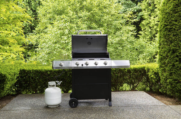 Large outdoor bbq cooker with lid in open position on home concr