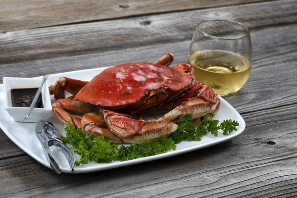 Whole Dungeness crab in dinner setting with wine on wooden table — Stockfoto