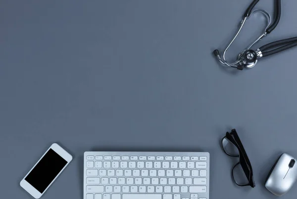 由医生的医疗设备 带听诊器的灰桌 计算机键盘 手机和阅读眼镜组成的平面布局中的卫生保健概念 带有复制空间的顶部视图 — 图库照片
