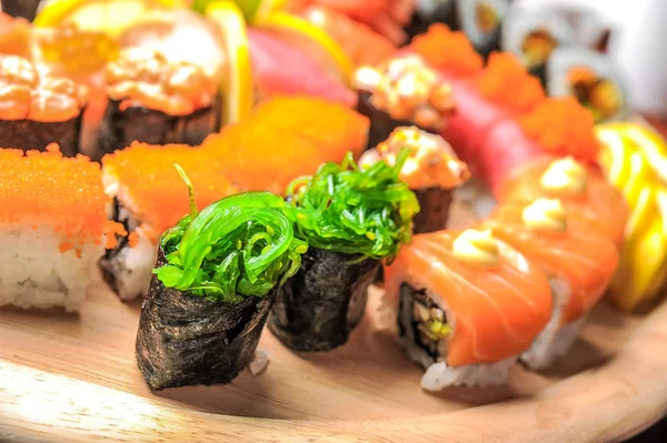 Nigiri sushi och rullar med fisk serveras på träbord — Stockfoto