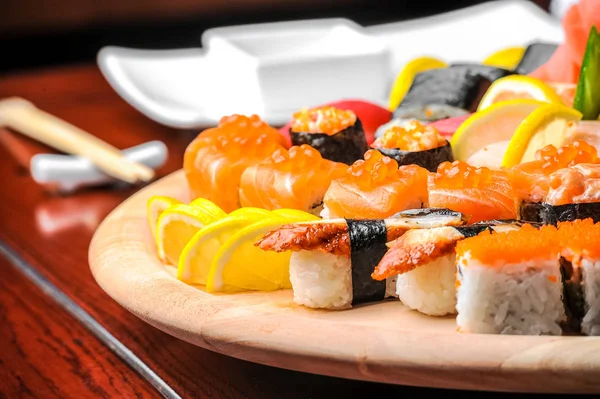 Суши и булочки с рыбой, подаваемые на деревянном столе — стоковое фото