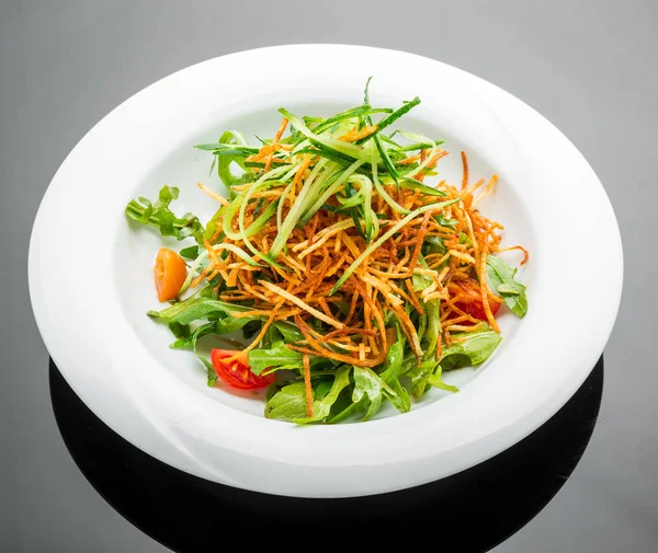 Вегетаріанський салат зі смаженими картопляними чіпсами та руколою на тарілці — стокове фото