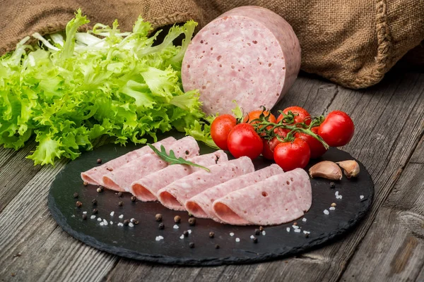 Cut sausage from ham on a wooden background — Stock Photo, Image