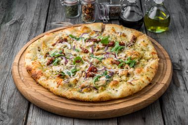 Pizza güneşte kurutulmuş domates, jambon, roka ve parmesan peyniri ile