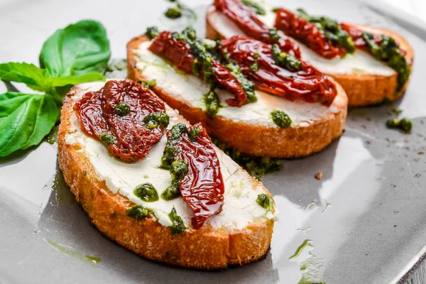 Sabrosos aperitivos italianos salados, o bruschetta, en rebanadas de baguette tostada adornada con albahaca —  Fotos de Stock