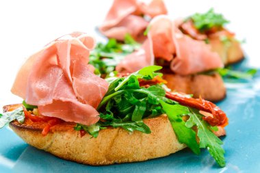 Lezzetli lezzetli İtalyan meze veya bruschetta, dilim tost baget fesleğen ile süslenmiş üzerinde