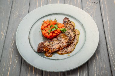 Ahşap bir masada soslu ızgara et ve haşlanmış sebze.