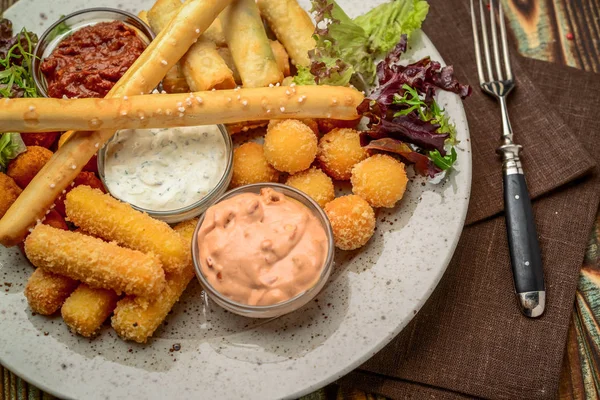 Allsorts of fried snacks with two different sauces on black background — Stock Photo, Image