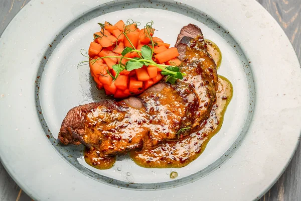 Gegrild vlees met saus en gestoofde groenten op een houten tafel — Stockfoto