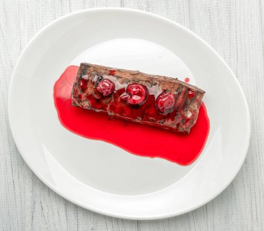 Beyaz tabakta kiraz soslu biftek.