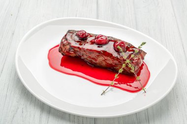 Beyaz tabakta kiraz soslu biftek.