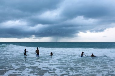 Karon sahilinde gün batımı. Sörf yapan insanların siluetleri. Phuket, Tayland 