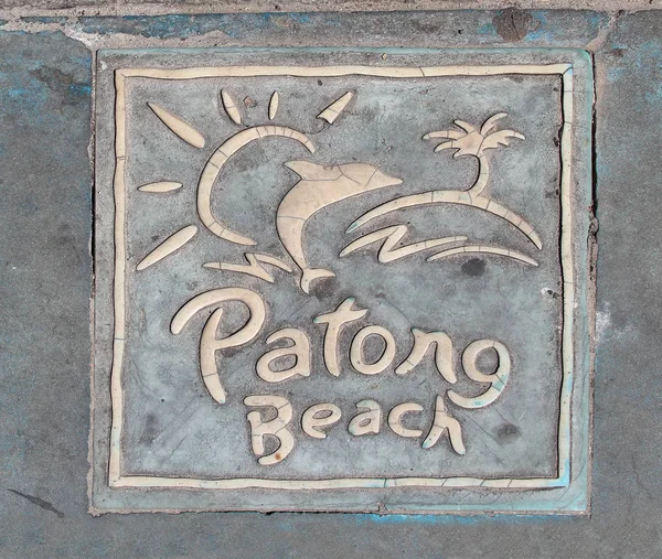 Pavement tile with a Patong Beach logo on a sidewalk of a street in Patong, Phuket, Thailand
