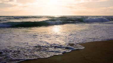 Beautiful sunset on tropical beach. The surf pounds the shore. Karon beach, Phuket, Thailand
