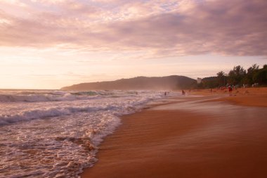 Beautiful sunset on tropical beach. The surf pounds the shore. Karon beach, Phuket, Thailand