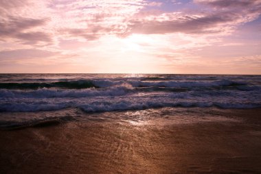 Beautiful sunset on tropical beach. The surf pounds the shore. Karon beach, Phuket, Thailand
