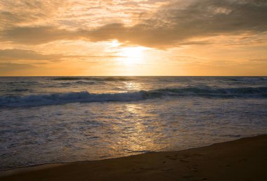 Beautiful sunset on tropical beach. The surf pounds the shore. Karon beach, Phuket, Thailand