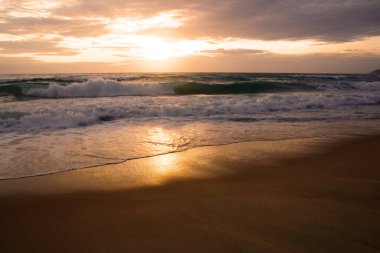 Beautiful sunset on tropical beach. The surf pounds the shore. Karon beach, Phuket, Thailand