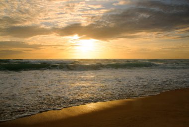 Beautiful sunset on tropical beach. The surf pounds the shore. Karon beach, Phuket, Thailand
