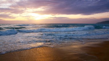 Beautiful sunset on tropical beach. The surf pounds the shore. Karon beach, Phuket, Thailand