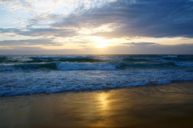 Beautiful sunset on tropical beach. The surf pounds the shore. Karon beach, Phuket, Thailand