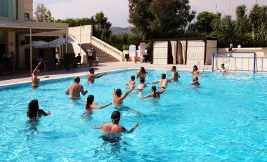 Afandou Village, Rhodes, Yunanistan - 26 Temmuz 2019: Tanımlanamayan otel misafirleri su topu oynuyor ve Dessole Lippia Golf Resort Hotel 'deki havuzda eğleniyor
