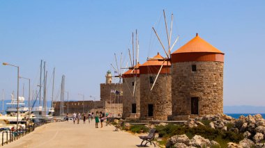 MANDRAKI HARBour, RHODES, GREECE - 18 Mart 2020: Rıhtım ve ortaçağ kalesi ve yel değirmenleri, Rodos, Yunanistan
