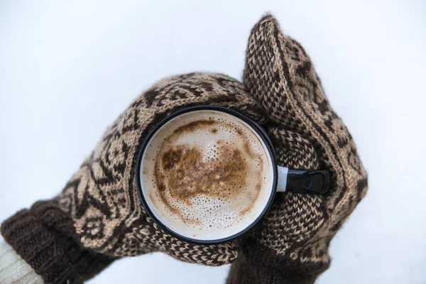 Kobieta trzyma filiżankę kawy z mlekiem w ciepłych rękawiczkach — Zdjęcie stockowe