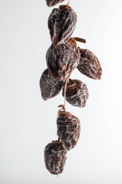 Beyaz arka planda ipe asılmış kurumuş hurma.