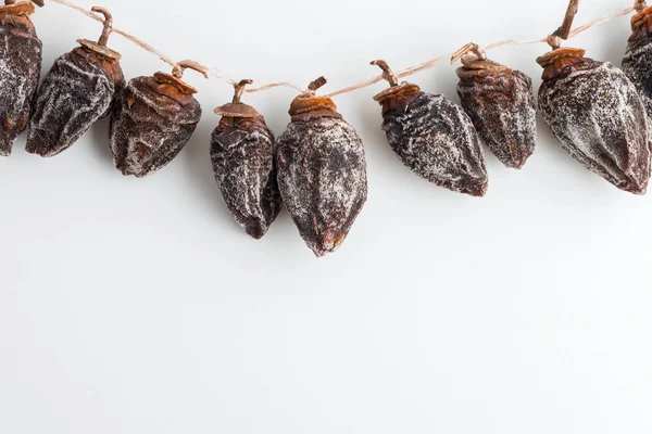 Dried persimmon hanging on rope on white background — Stock Photo, Image