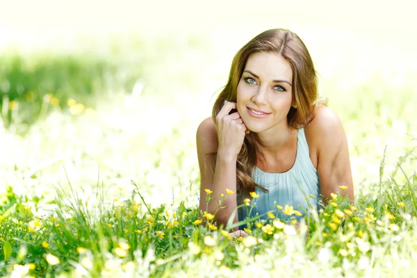 Jonge vrouw in blauwe jurk liggen op gras — Stockfoto