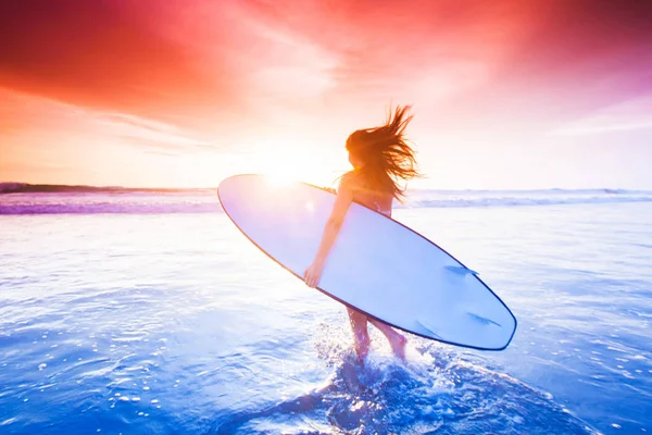 Surfer girl on beach at sunset — Stock Photo, Image