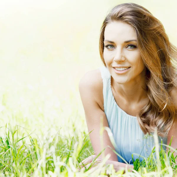 Young woman in blue dress lying on grass Stock Image