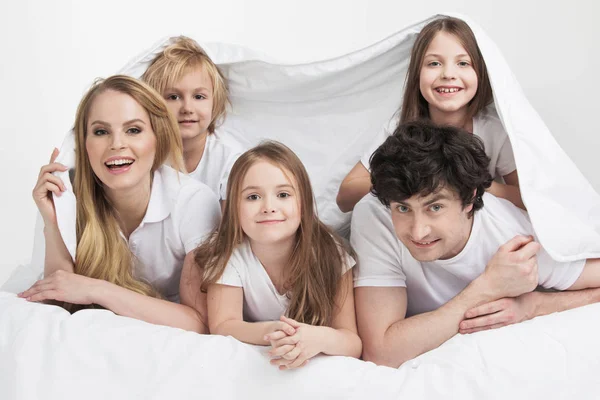 Família sorridente na cama — Fotografia de Stock