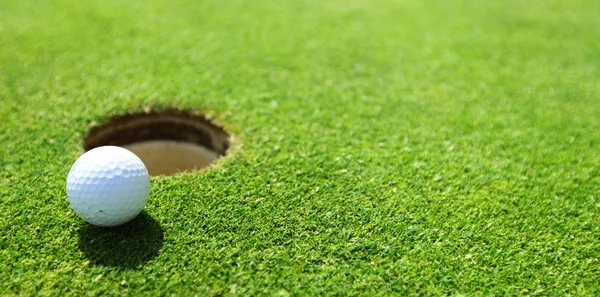 Golf ball on lip of cup — Stock Photo, Image