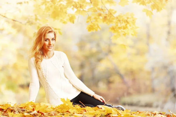 Woman sitting in autumn park — Stock Photo, Image