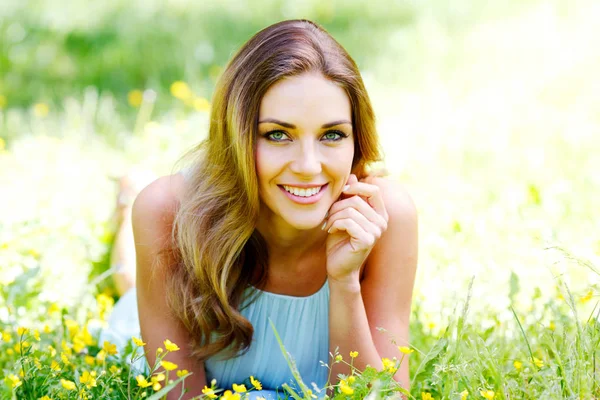 草の上に横になっている青いドレスの若い女性 — ストック写真