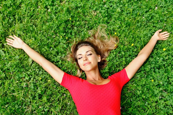 Молодая женщина в красном платье лежит на траве — стоковое фото