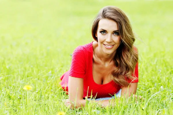 Молодая женщина в красном платье лежит на траве — стоковое фото