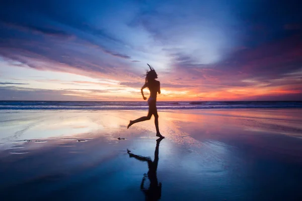 Mulher correndo na praia ao pôr do sol — Fotografia de Stock