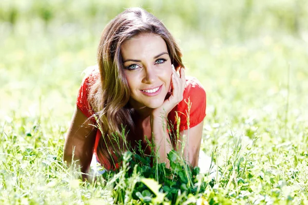 美しいです若いです女性で赤いドレス草の上に横たわる — ストック写真