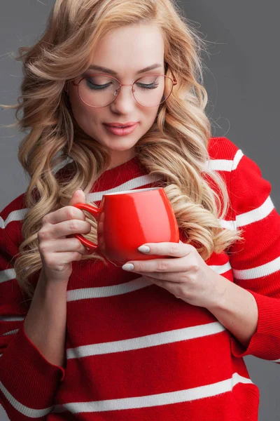 Hermosa mujer en vasos sosteniendo taza roja — Foto de Stock