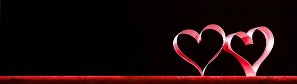 Červená stuha srdce na černé — Stock fotografie