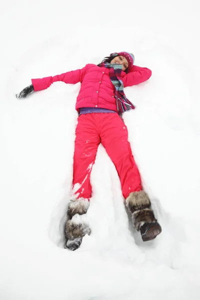 Mulher jovem que estabelece na neve — Fotografia de Stock