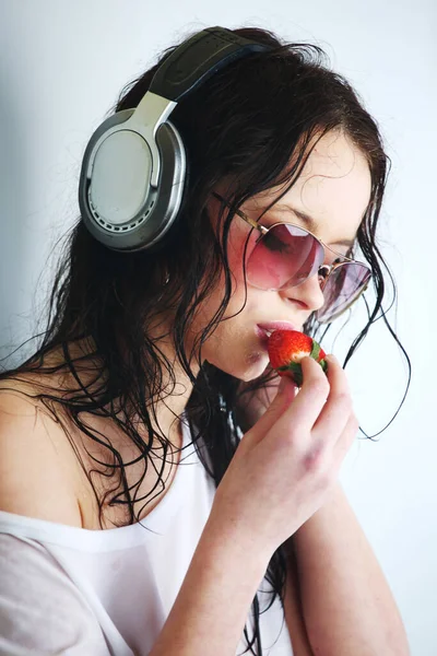 Junge Frau Hört Musik Über Kopfhörer Und Isst Erdbeere Nahaufnahme — Stockfoto