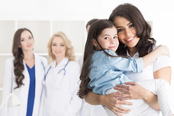 诊所的母亲和女儿 有背景的医生团队 — 图库照片
