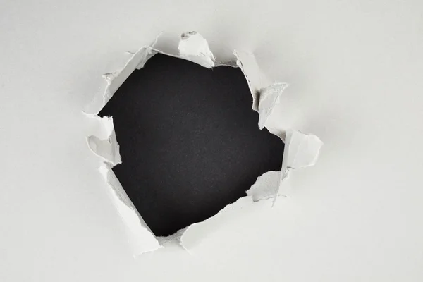 Buraco negro em papel cinzento rasgado — Fotografia de Stock