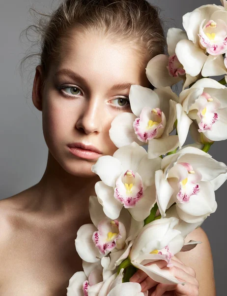 Junge Frau Mit Weißen Orchideenblüten Auf Grauem Hintergrund — Stockfoto