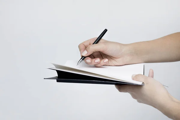 Quaderno con una penna primo piano nelle mani delle donne su un bac bianco — Foto Stock